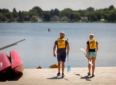 People carrying paddles towards lake